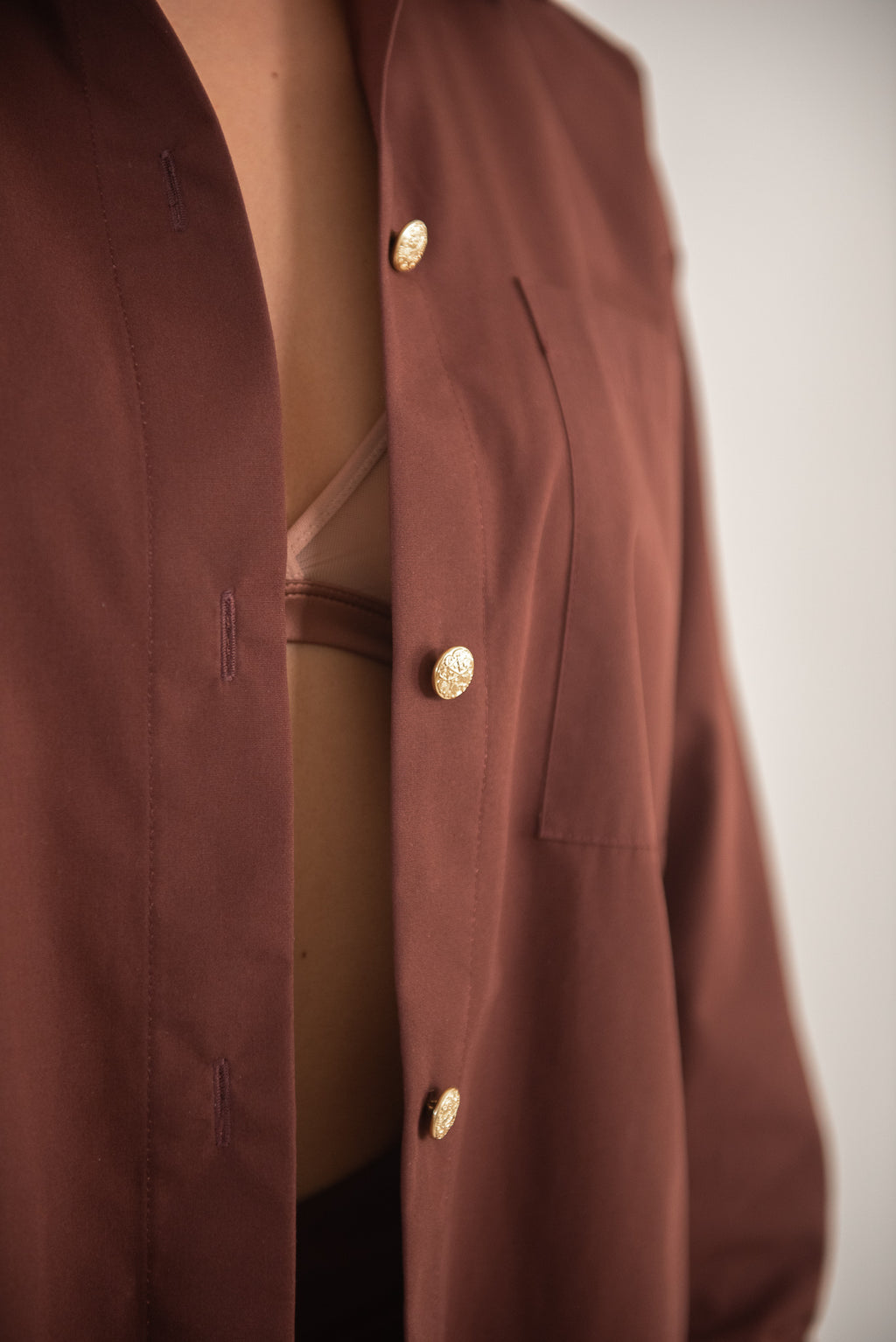 Close-up of brown shirt showing buttons and fabric texture.