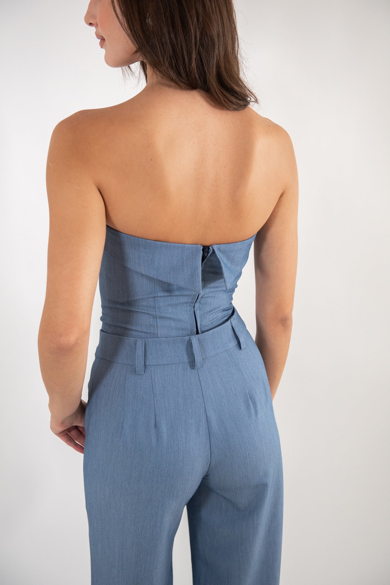 Woman wearing blue top, full-body back view.