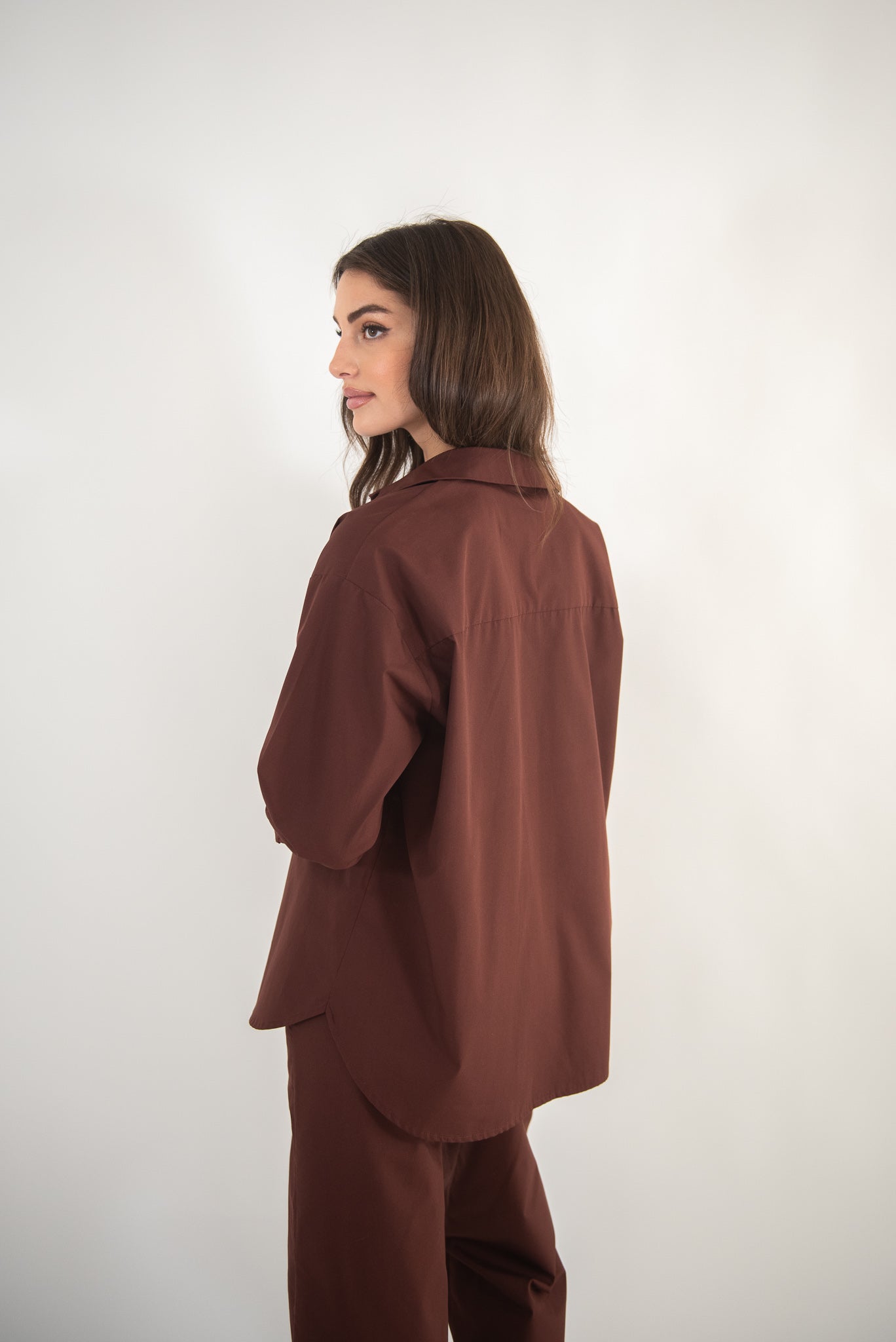 Woman wearing a brown shirt, side view.