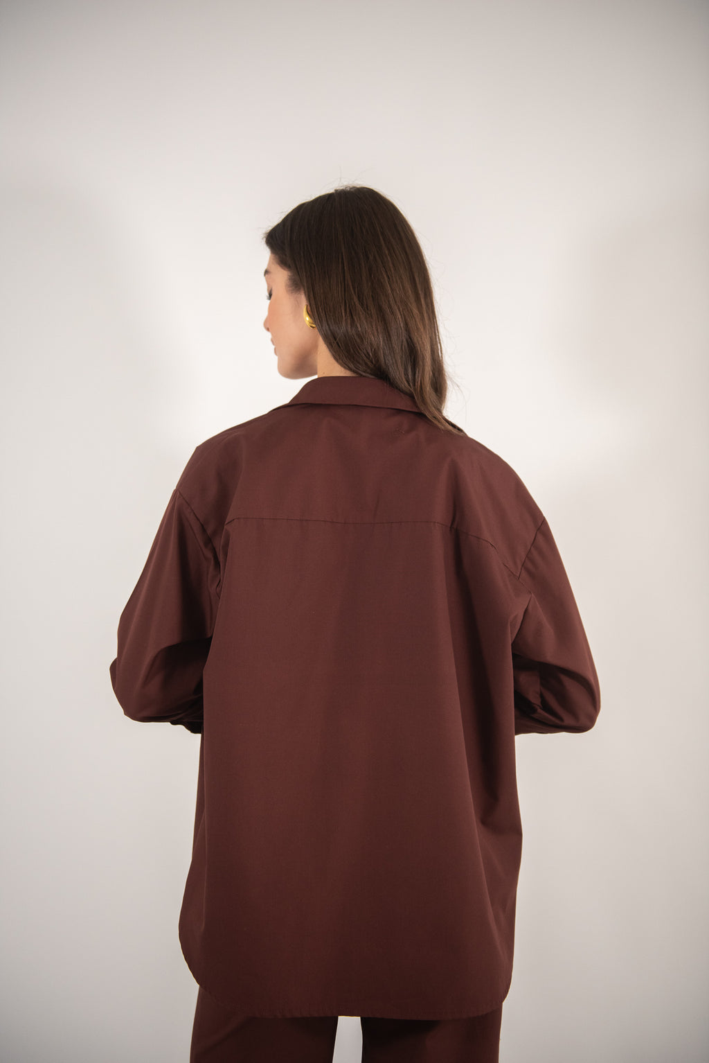 Woman wearing a brown shirt, back view.