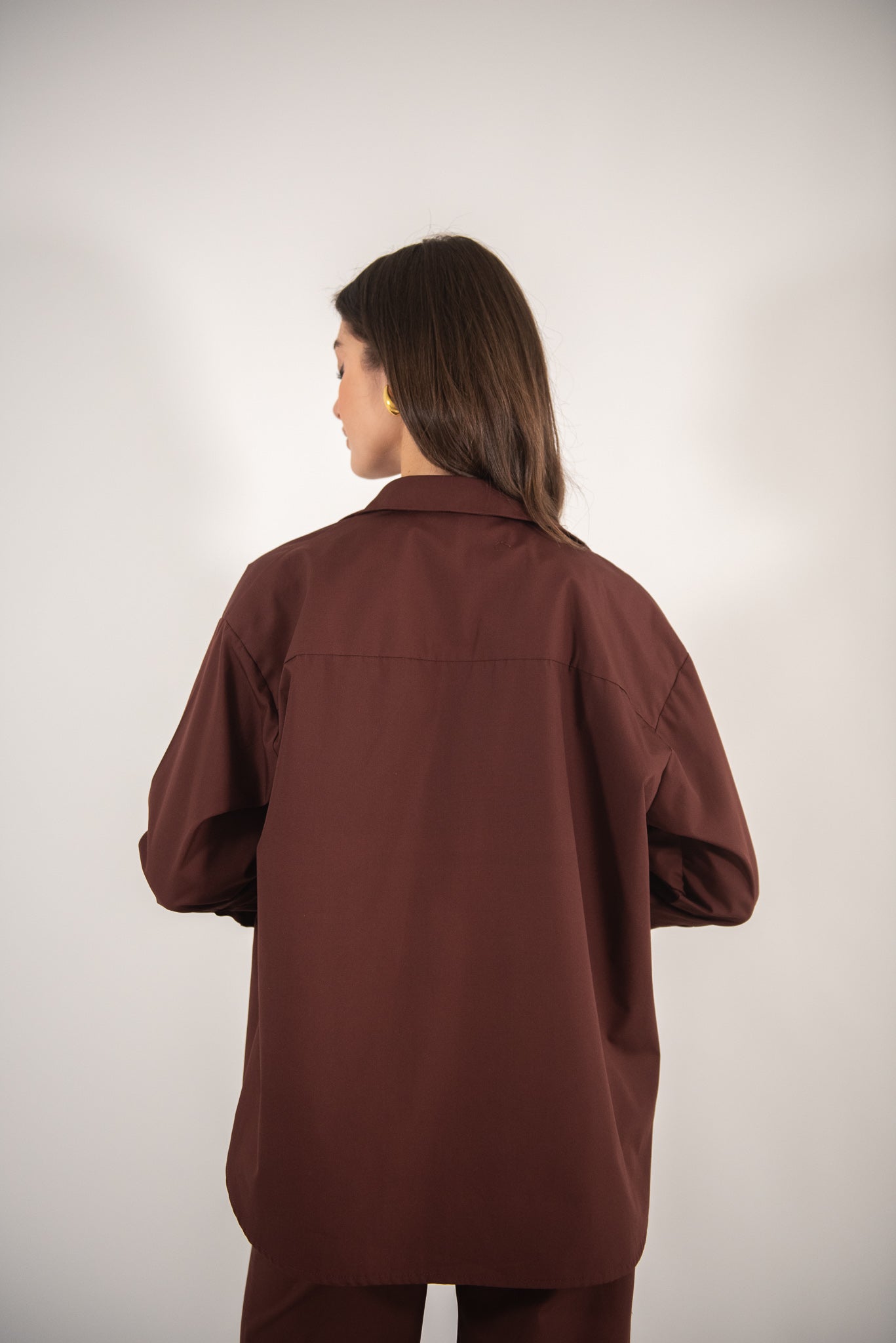 Woman wearing a brown shirt, back view.