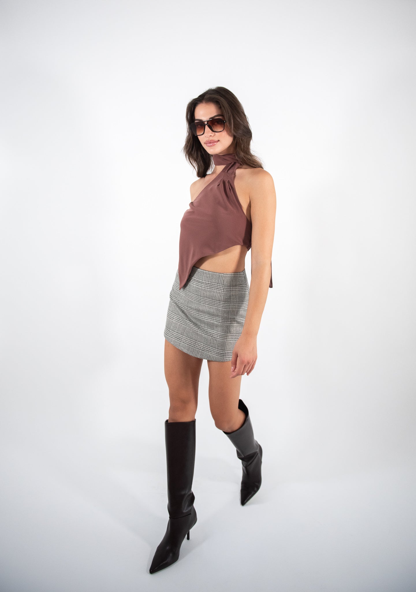 Woman posing like walking in a brown top and checkered skirt