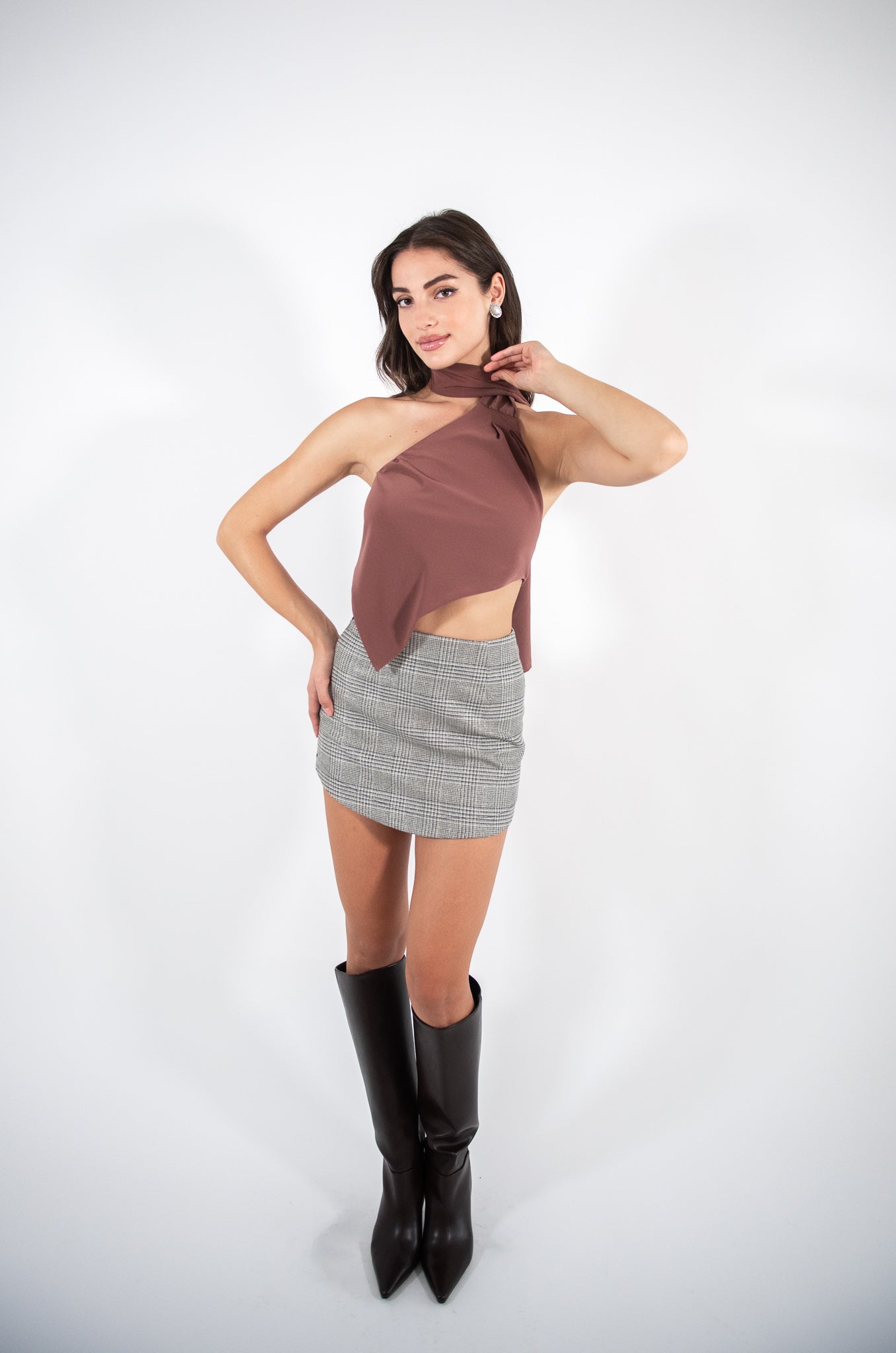 Woman posing in a brown top and checkered skirt