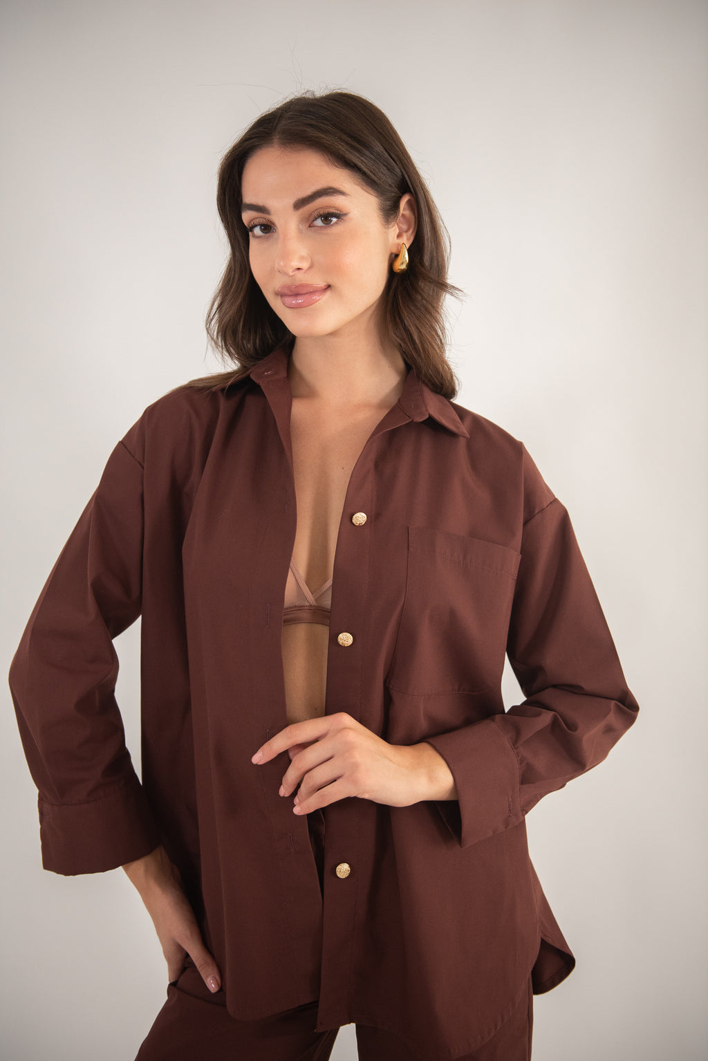 Woman wearing a brown shirt and looking at the camera, top-body view