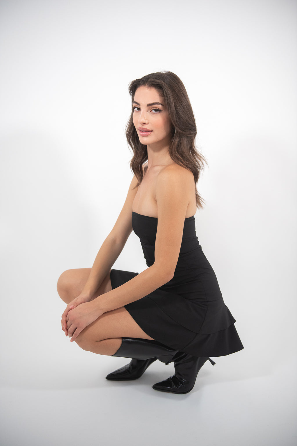 Woman sitting down wearing black dress.